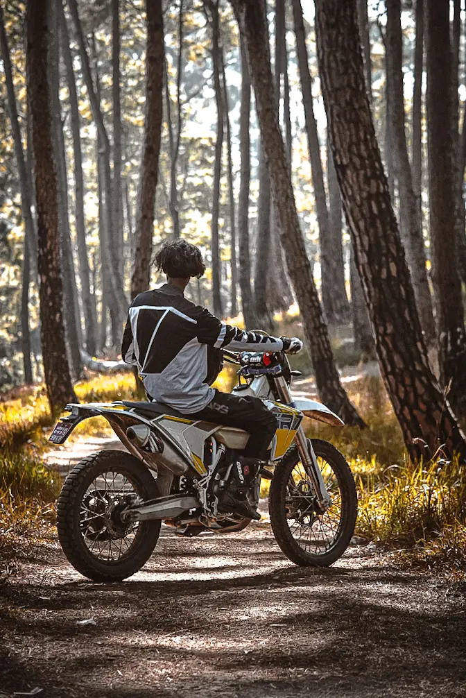Motorbike rider paused on a sunlit forest trail