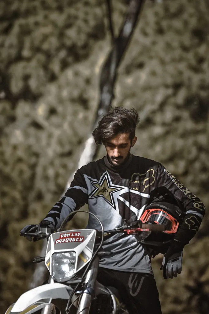Tejson resting beside a motorbike on a forest ride