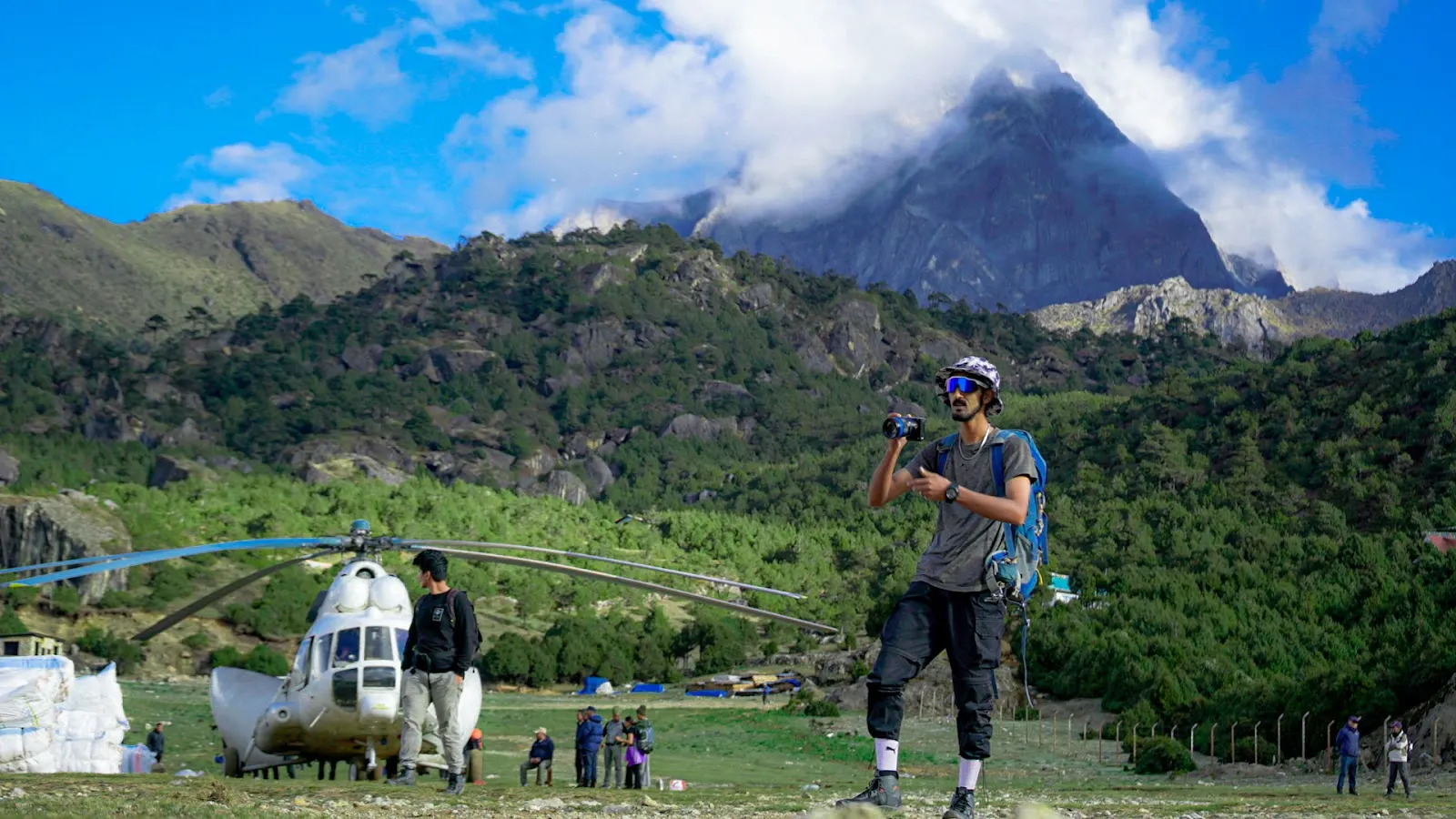 Filmmaker holding a camera beside a mountain helicopter landing area