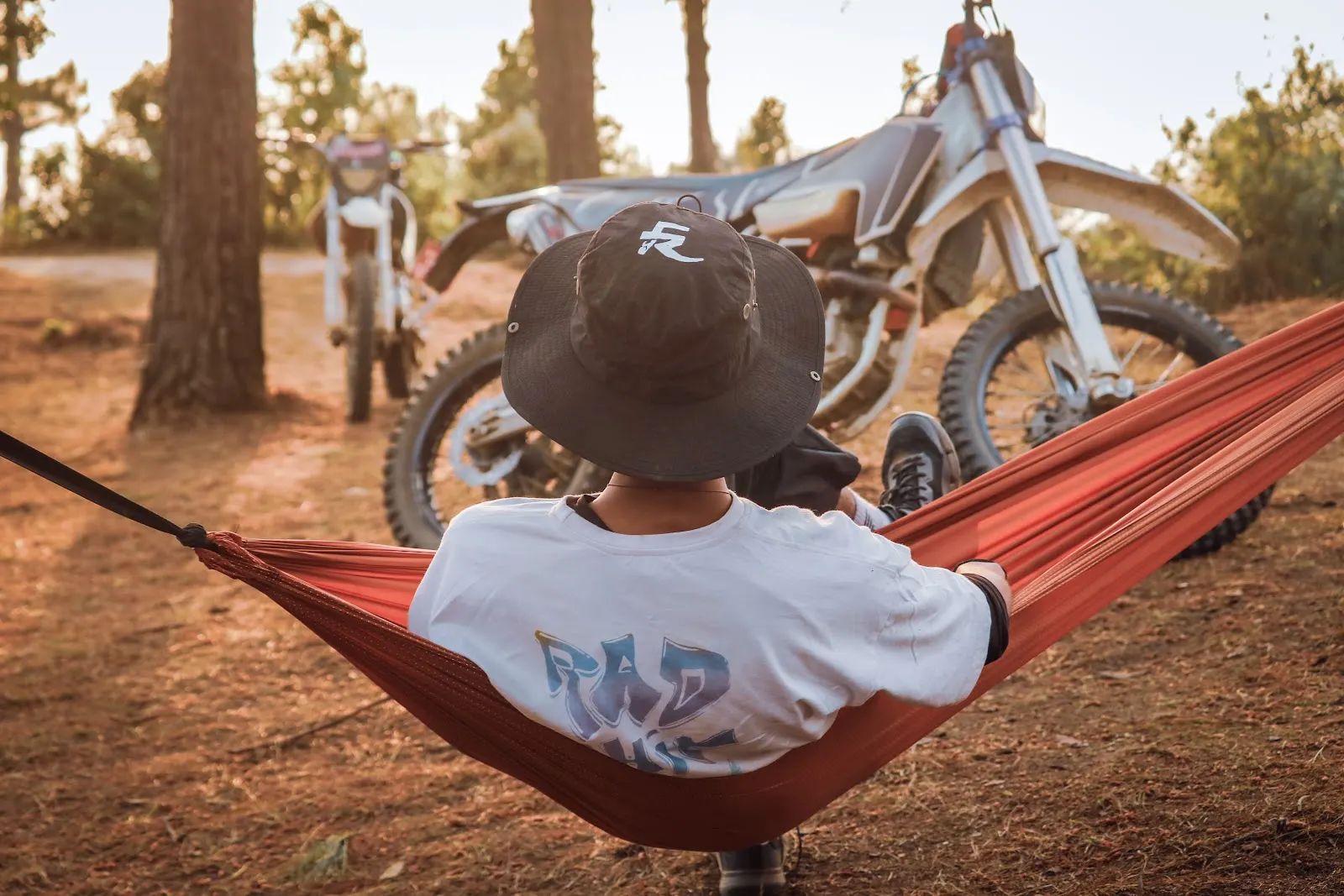 A rider resting in a hammock near bikes in the forest