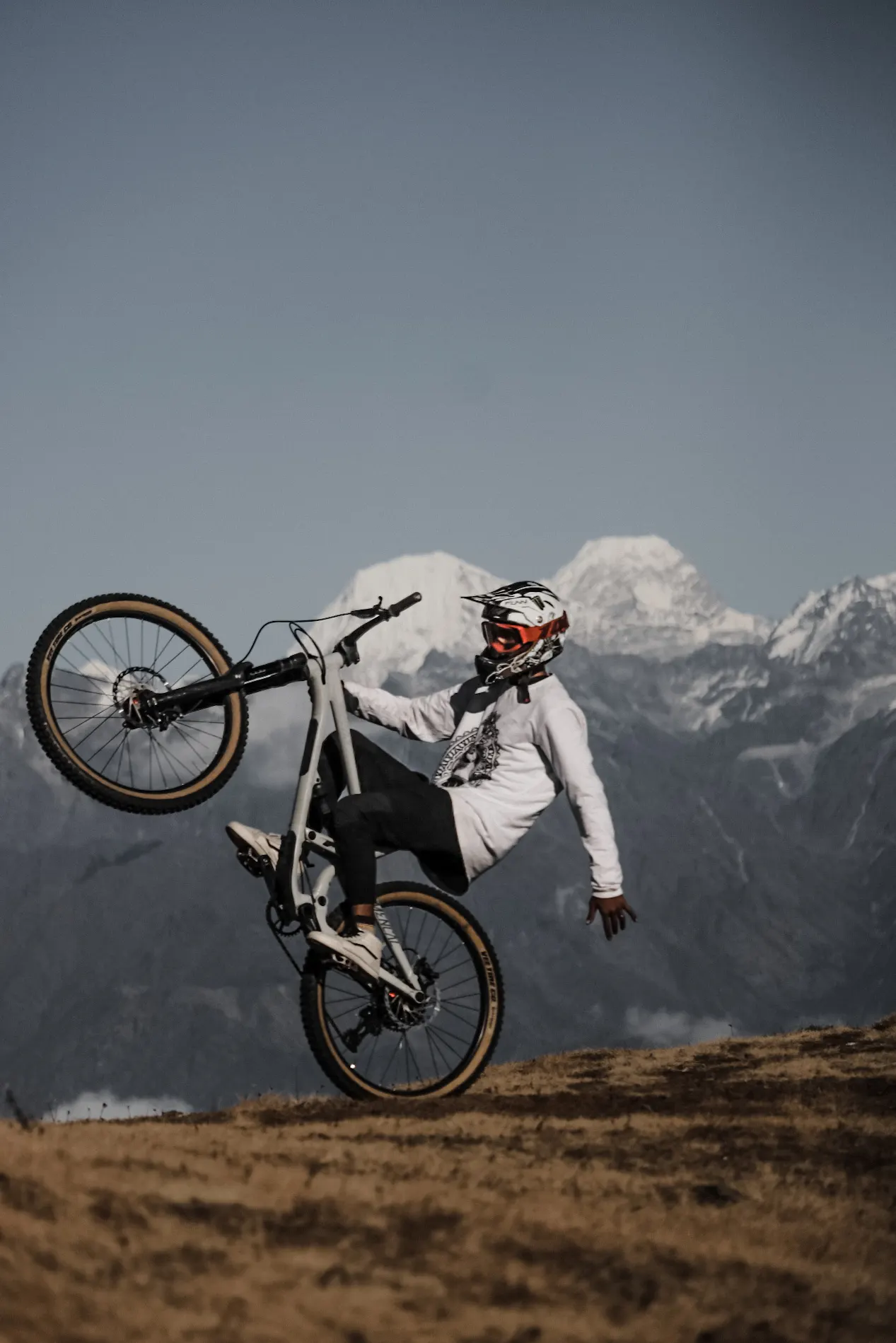 Mountain biker lifting the front wheel with snowy mountains behind